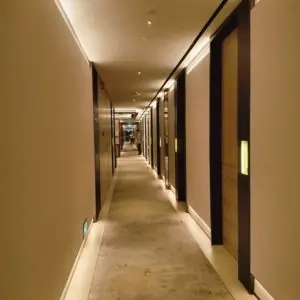 A long Dubai corridor with patterned carpet, illuminated by a light in the center, creating a warm atmosphere.