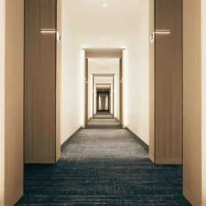 A long hallway in Dubai featuring wooden doors and a patterned carpet.