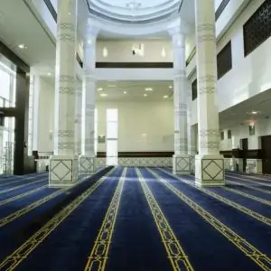 Interior of a large mosque in Dubai featuring a vibrant blue carpet covering the floor.