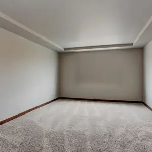 An empty room featuring a carpet, with neutral-colored walls and natural light streaming in.