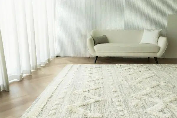 Elegant living room featuring a beige sofa, sheer curtains, and a textured area rug in dubai