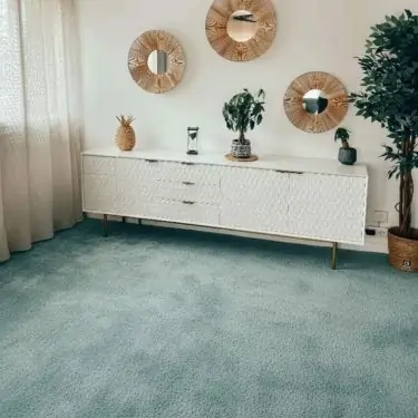 Interior Decoration Company in Dubai installing modern beige carpet tiles in a spacious hallway with large windows and bright lighting.